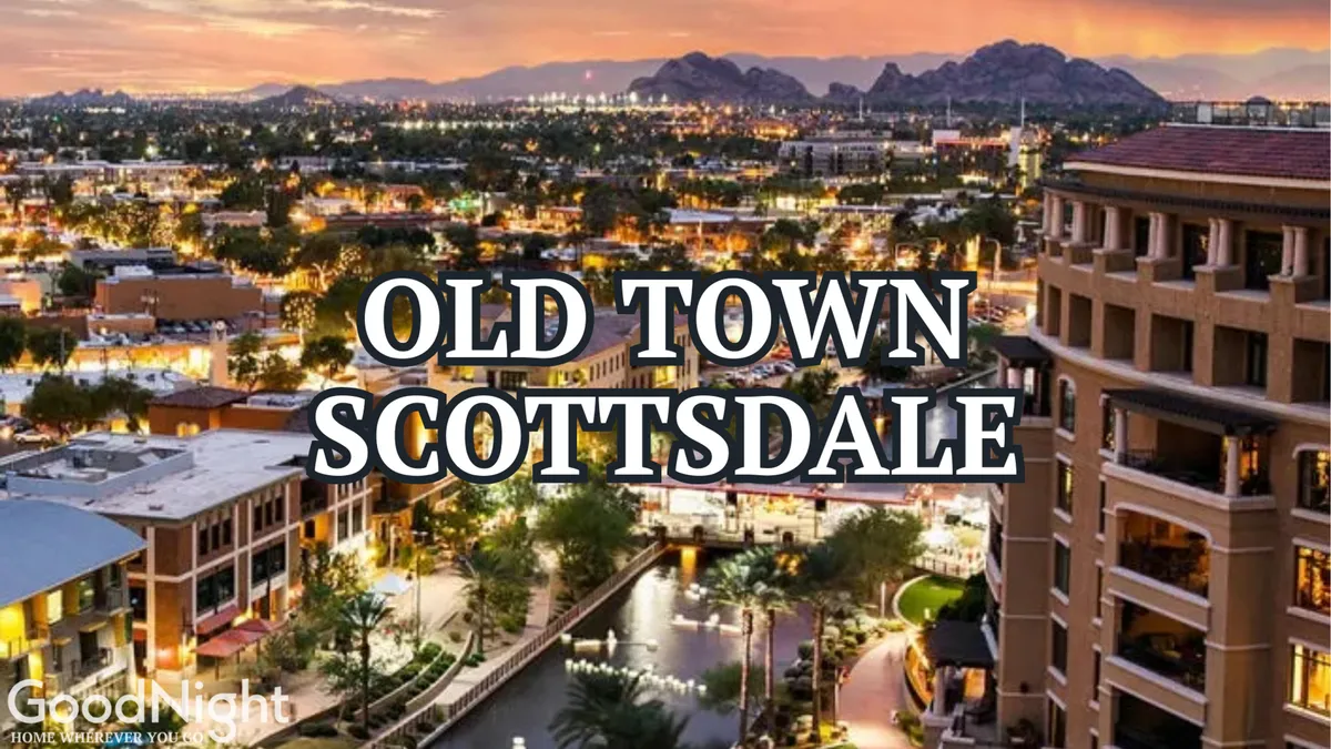 A picturesque evening view of Scottsdale’s illuminated waterfront district, featuring vibrant buildings, a lively waterway, and distant mountain silhouettes. The scene is energetic and welcoming, suggesting a variety of family-friendly dining, shopping, and entertainment experiences.