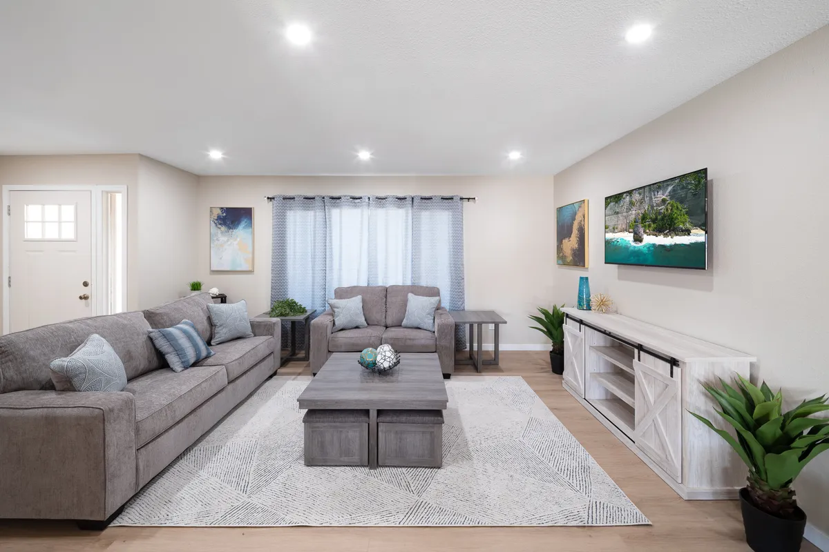 A cozy and inviting living area with a plush sofa set, a central coffee table ideal for board games, tasteful wall art, and a window with flowing curtains. The mood is relaxed and sociable, making it an excellent setting for both board games and casual group activities.