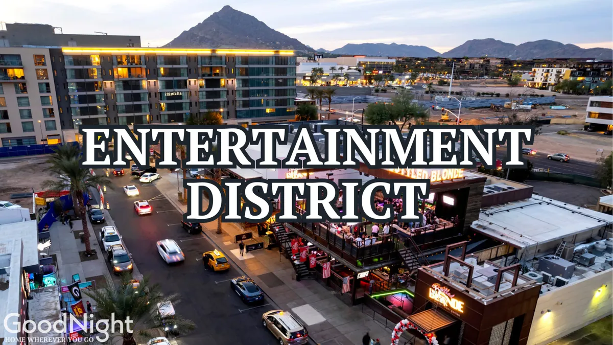 This image captures the vibrant energy of Scottsdale's Entertainment District, featuring lively signage, outdoor seating, cars lining the street, and mountains in the background. The setting is bustling and inviting, suggesting a hub of nightlife, dining, and city excitement.